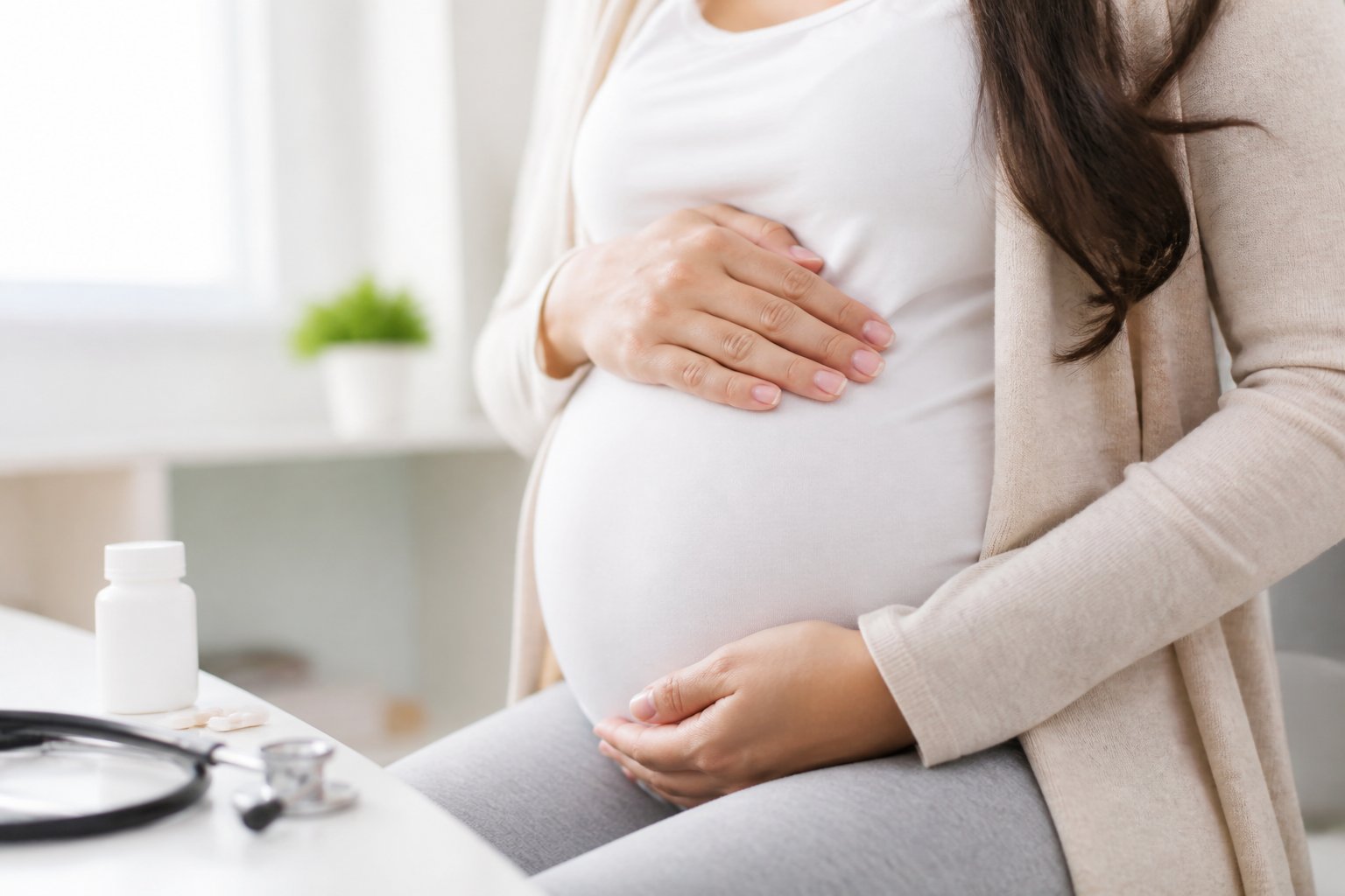 Mulher grávida tocando suavemente a barriga em ambiente médico tranquilo.
